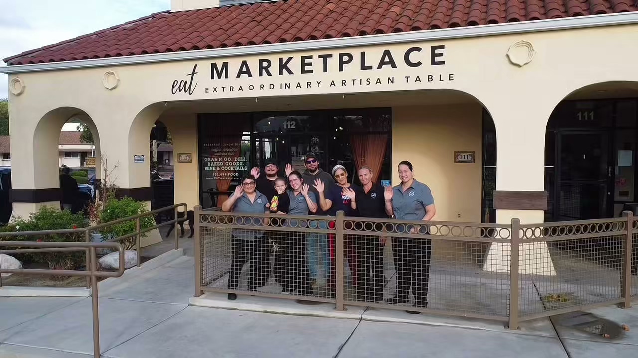 The EAT Marketplace team waving outside the storefront in Old Town Temecula